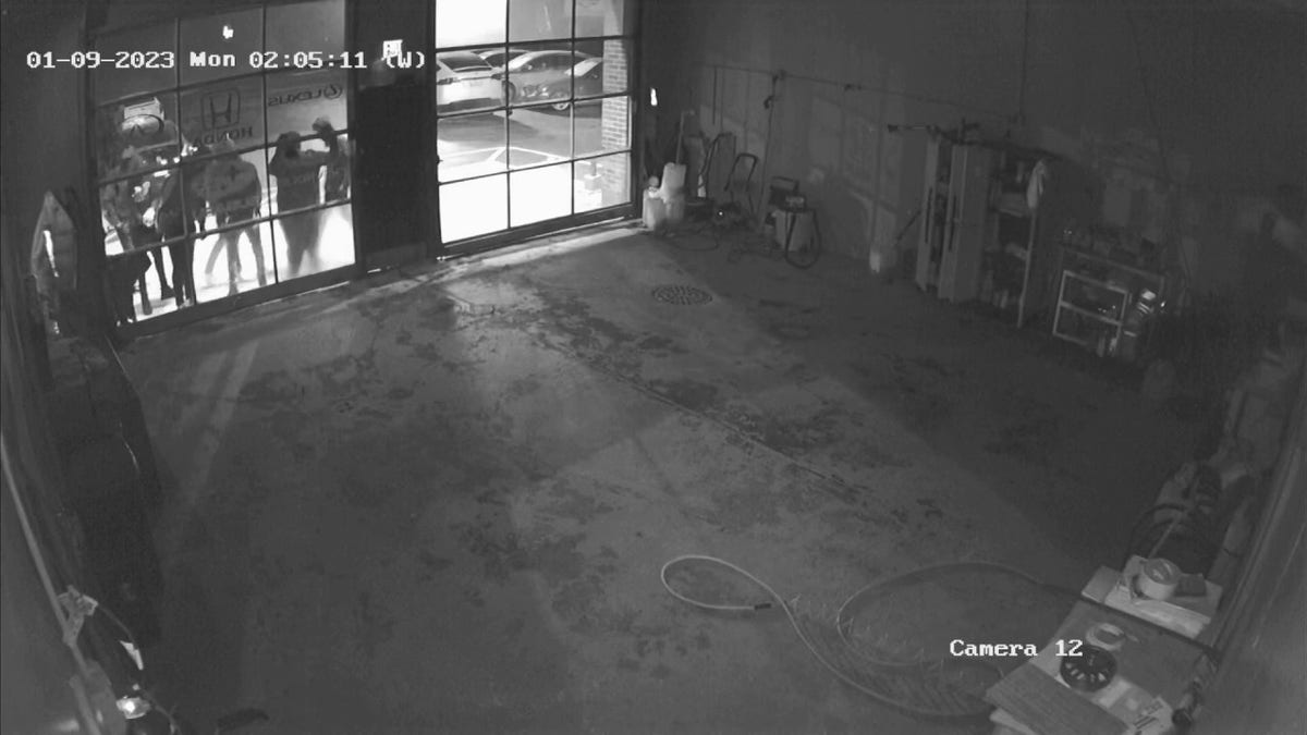 Thieves peer through the window at a luxury car dealership