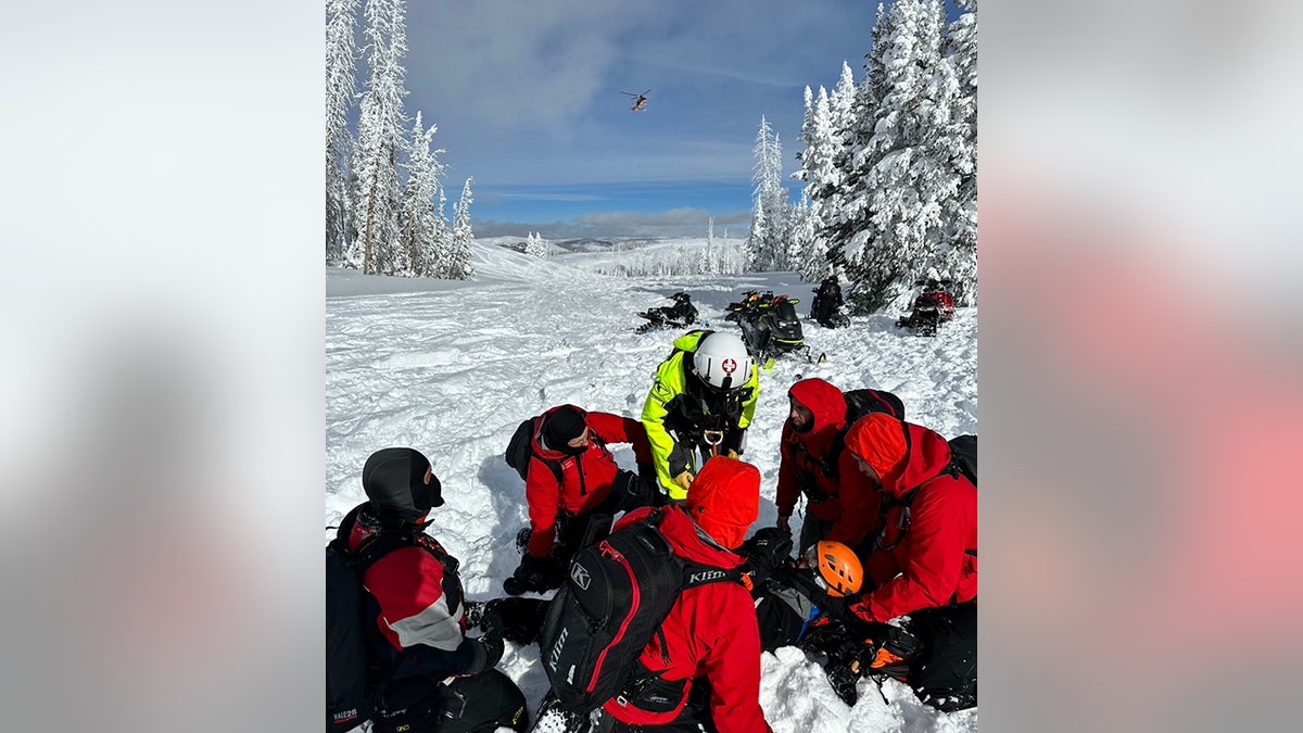 rescuers helping snowmobiler on mountain