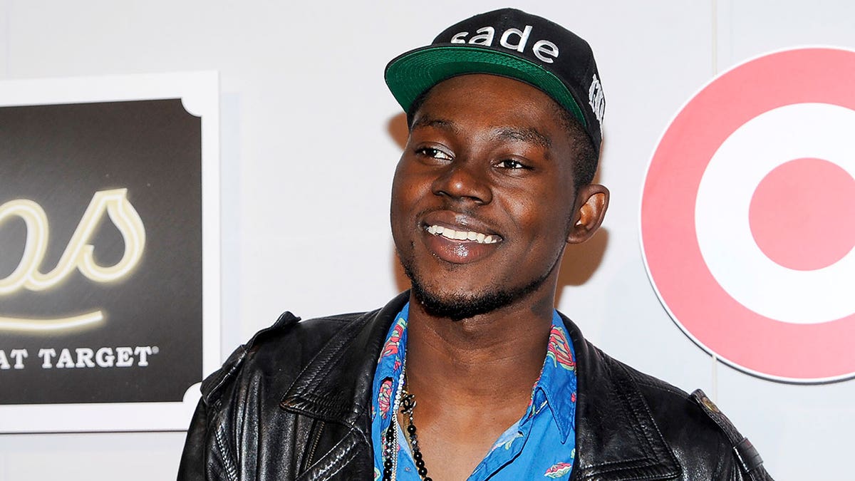 Theophilus London smiles at a red carpet event