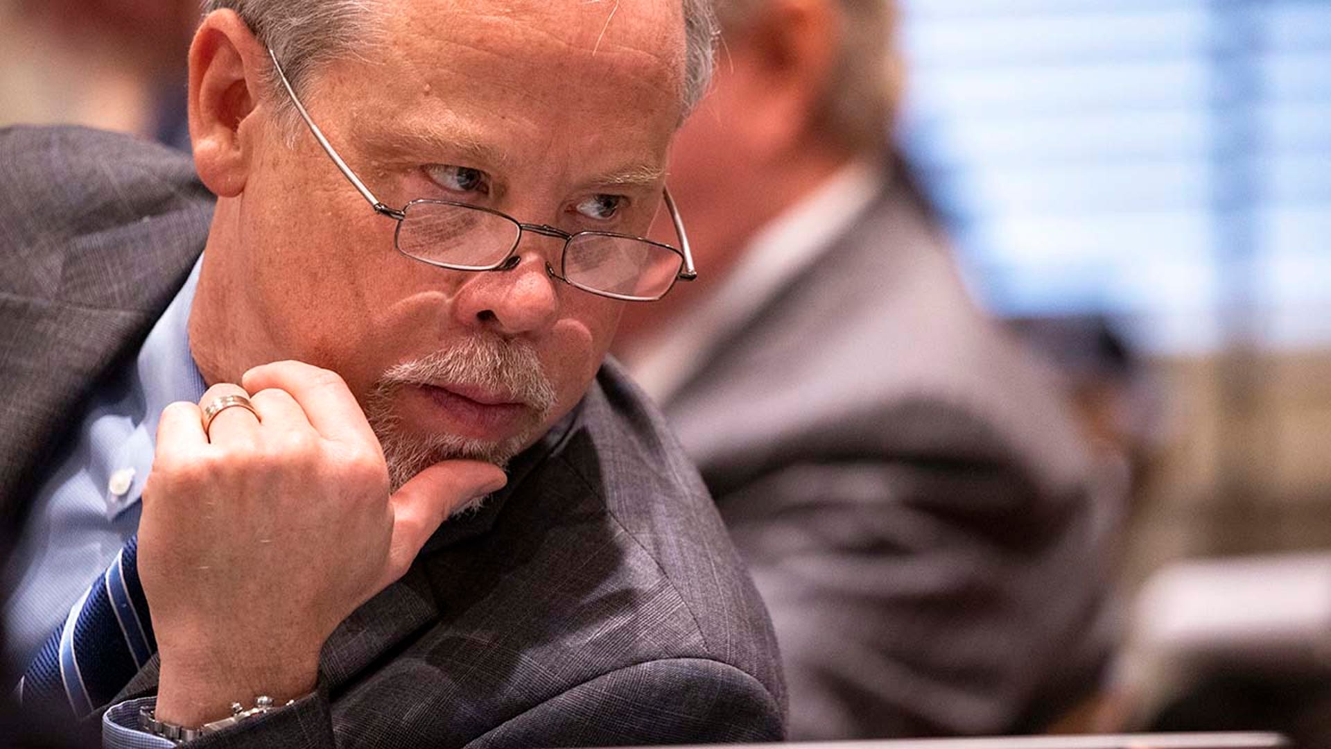 A man wearing glasses looks on.