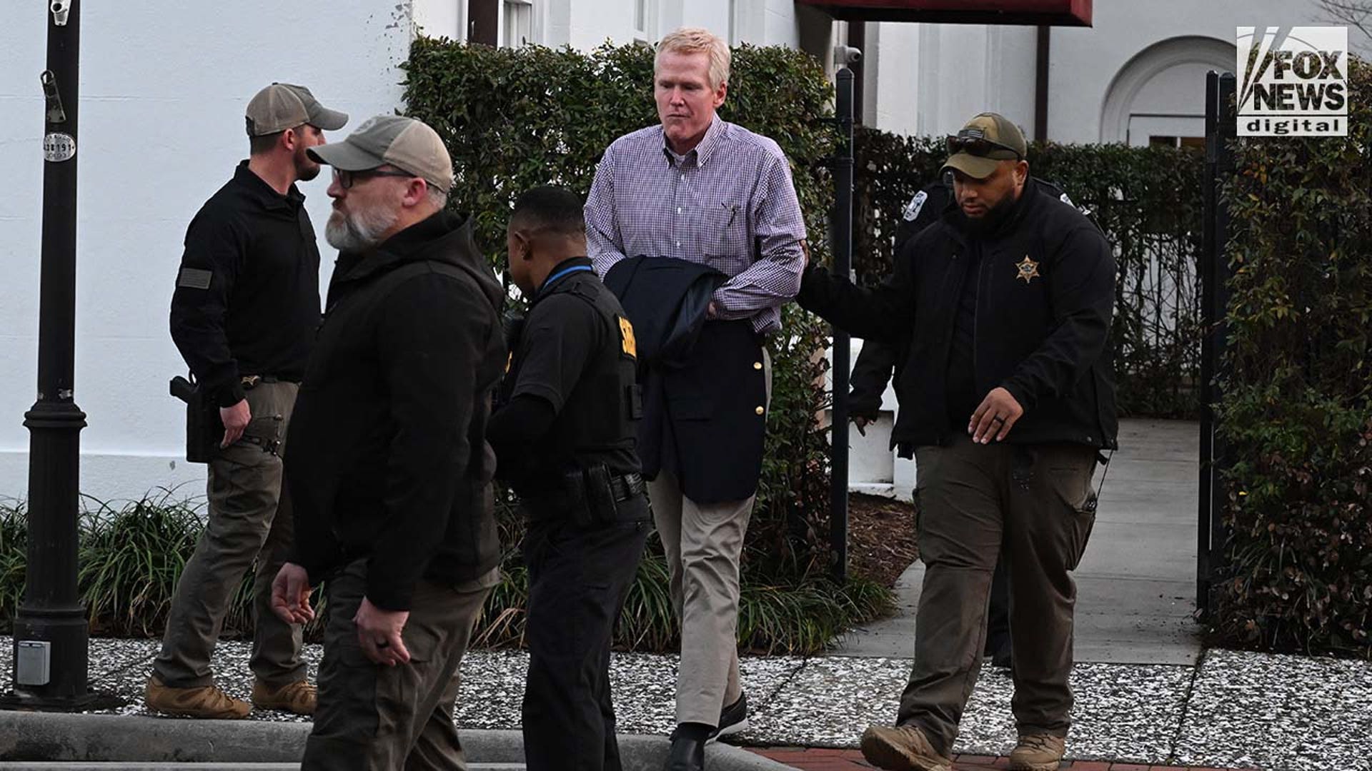 A man is escorted out of a courthouse by police.