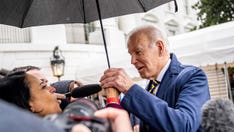 Biden grabs NBC reporter's hand as he steps underneath her umbrella to answer her question
