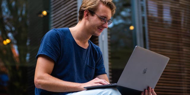 Seorang pria tersenyum pada Macbook-nya