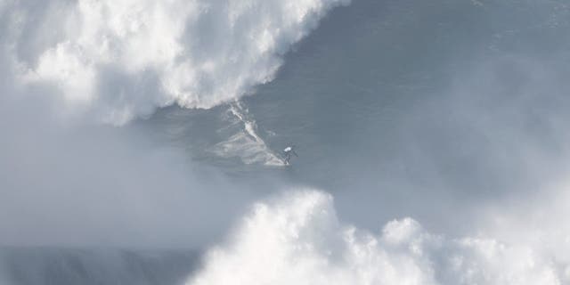 A surfer rides a wave in Praia do Norte, Nazare, Portugal, on January 8, 2022. 