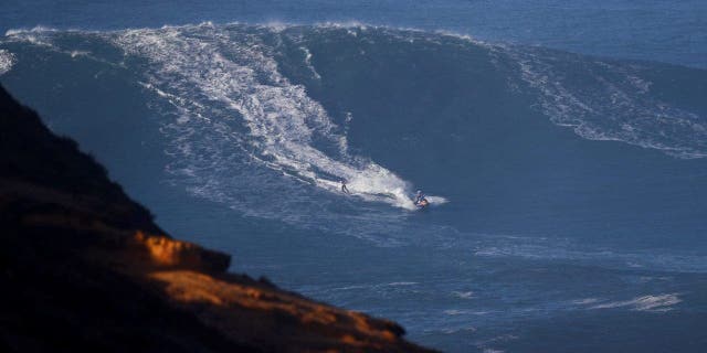 A surfer is towed-in, in Praia do Norte, Nazare, Portugal, January 8, 2022. REUTERS/Pedro Nunes