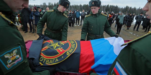Military cadets cover the coffin of Dmitry Menshikov with a flag in the Alley of Heroes at a cemetery in St. Petersburg, Russia, Dec. 24, 2022.