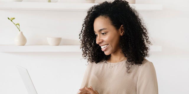 Woman sitting at the table staring happily at the computer because she followed CyberGuy's advice and successfully cleared out all her existing autofill data.