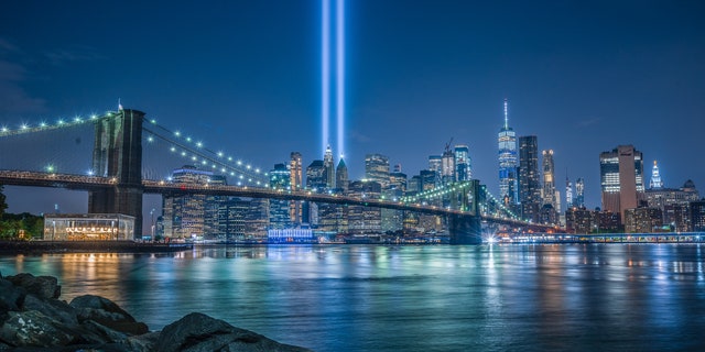 The Brooklyn Bridge in front of a 9/11 Tribute in Light in New York City.