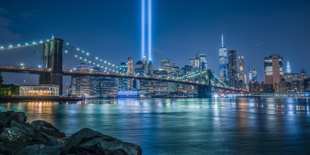 The Brooklyn Bridge in front of a 9/11 Tribute in Light in New York City.