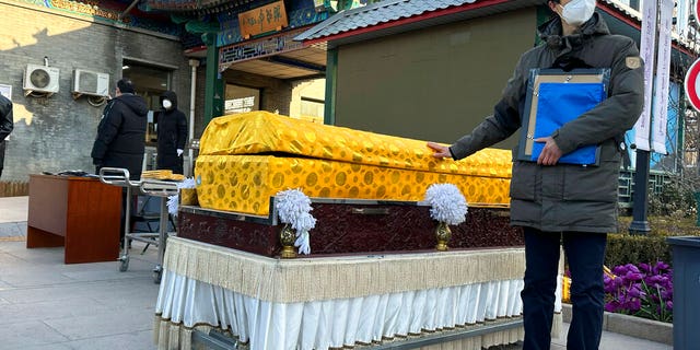 A man places his hand on a casket outside a crematorium in Beijing on Dec. 31, 2022.