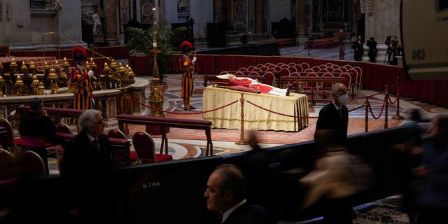 People look at the body of late Pope Emeritus Benedict XVI laid out in state inside St. Peter's Basilica at The Vatican, Monday, Jan. 2, 2023.