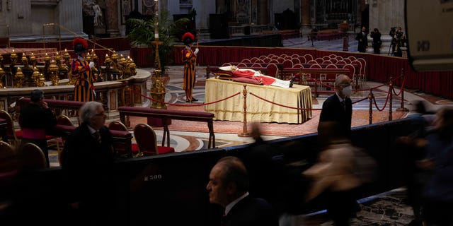 People look at the body of late Pope Emeritus Benedict XVI laid out in state inside St. Peter's Basilica at The Vatican, Monday, Jan. 2, 2023.