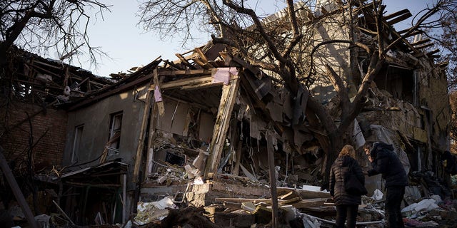 Serhii Kaharlytskyi, right, stands outside his home, destroyed after a Russian attack in Kyiv, Ukraine, Monday, Jan. 2, 2023. Kaharlytskyi's wife Iryna died in the attack on Dec. 31, 2022. 