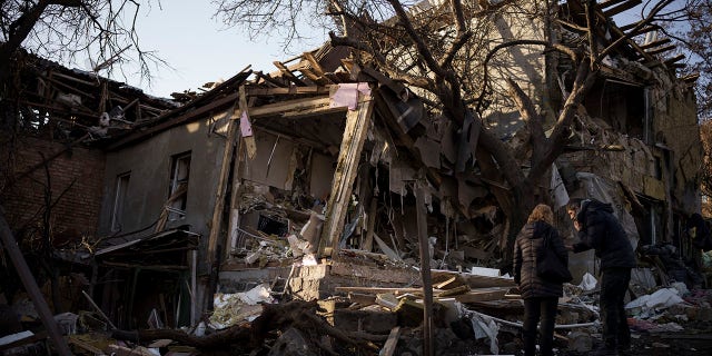 Serhii Kaharlytskyi, right, stands outside his home that was destroyed after a Russian attack in Kyiv, Ukraine, Monday, Jan. 2, 2023. Kaharlytskyi's wife Iryna died in the attack on Dec. 31, 2022.