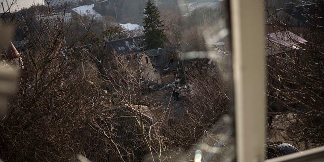 Damaged houses are seen through a broken window, following a Russian attack on New Year's Eve, in Kyiv, Ukraine, Monday, Jan. 2, 2023.