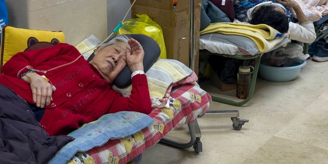 Elderly patients rest in the corridor of a Beijing hospital while receiving intravenous drips on January 5, 2023. The patients, mostly elderly, were on stretchers in the corridors and receiving oxygen while sitting in wheelchairs as the COVID-19 continues to increase in Chinese capital.