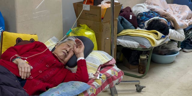 Elderly patients rest along a Beijing hospital corridor as they receive intravenous drips on Jan. 5, 2023. Patients, most of them elderly, were on stretchers in hallways and taking oxygen while sitting in wheelchairs as COVID-19 continues to surge in the Chinese capital.