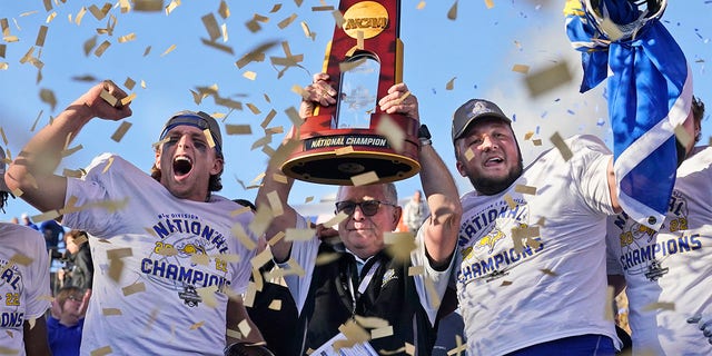 South Dakota State head coach John Stiegelmeier, center, celebrates with quarterback Mark Gronowski, left, and offensive lineman Mason McCormick with the trophy after they defeated North Dakota State to win the FCS Championship Game on January 8, 2023, in Frisco, Texas. 