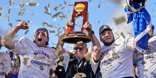 South Dakota State head coach John Stiegelmeier, center, celebrates with quarterback Mark Gronowski, left, and offensive lineman Mason McCormick with the trophy after they defeated North Dakota State to win the FCS Championship Game on January 8, 2023, in Frisco, Texas. 