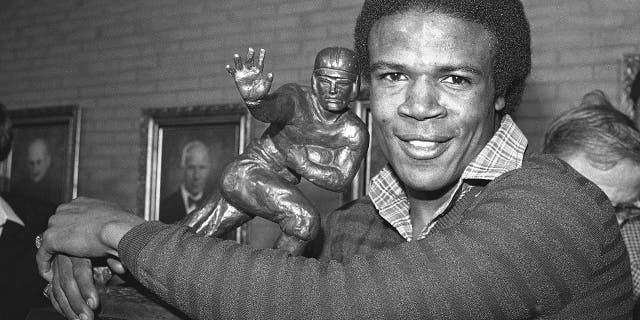 White'ın 3 Aralık 1979'da Los Angeles'ta 1979 Heisman Trophy'nin galibi ilan edilmesinin ardından, Güney Kaliforniya'nın geri dönüşü Charles White, 1968'de OJ Simpson tarafından kazanılan Heisman Trophy'ye sarılıyor.
