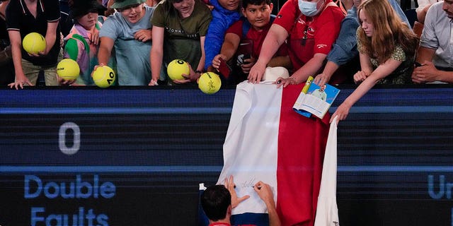 Daniil Medvedev autographs a Russian flag after defeating Marcos Giron at the Australian Open in Melbourne, Monday, January 16, 2023.