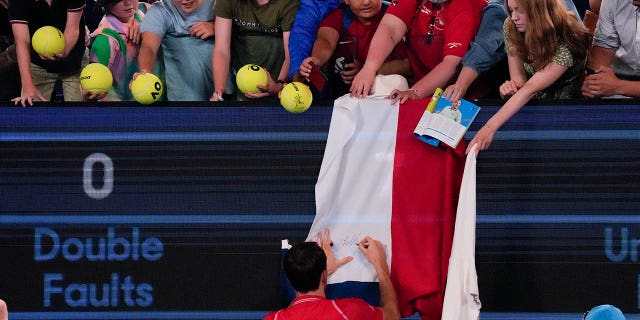 Daniil Medvedev of Russia autographs a Russian flag after defeating Marcos Giron of the U.S. in their first round match at the Australian Open tennis championship in Melbourne, Australia, Jan. 16, 2023. 