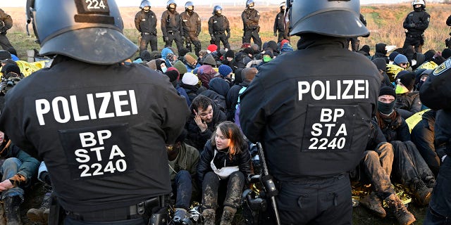 Police officers stand in front of a group of protesters, including Swedish climate activist Greta Thunberg, center bottom, on the edge of the Garzweiler II opencast lignite mine during a protest action by climate activists after the clearance of Luetzerath, Germany, Tuesday, Jan. 17, 2023. 