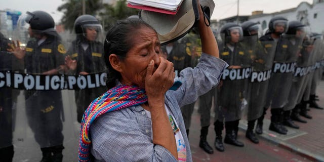 A woman carries a Bible in front of a line of riot police during a march by anti-government protesters who traveled to the capital from across the country to protest against Peruvian President Dina Boluarte in Lima, Peru, Wednesday, Jan. 18, 2023.