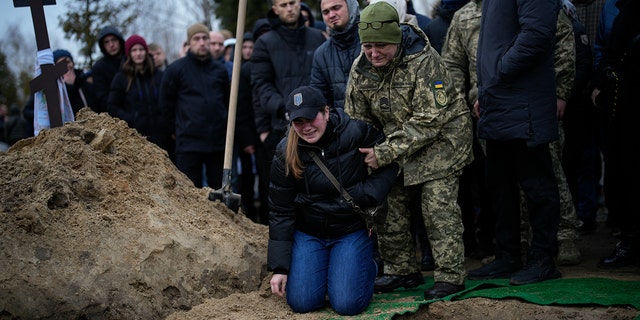 Anya Korostenska drops to her knees at the grave of her fiance, Oleksiy Zavadskyi, a Ukrainian serviceman who died in combat on Jan.15 in Bakhmut, during his funeral in Bucha, Ukraine, Jan. 19, 2023.