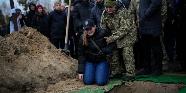 Anya Korostenska drops to her knees at the grave of her fiance, Oleksiy Zavadskyi, a Ukrainian serviceman who died in combat on Jan.15 in Bakhmut, during his funeral in Bucha, Ukraine, Jan. 19, 2023.