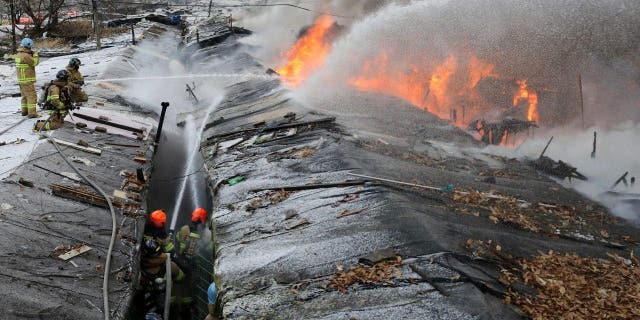 Firefighters battle a fire at Guryong village in Seoul, South Korea, Friday, Jan. 20, 2023. About 500 South Koreans were forced to flee their homes after a fire spread through a low-income neighborhood in southern Seoul on Friday morning and destroyed dozens of homes.