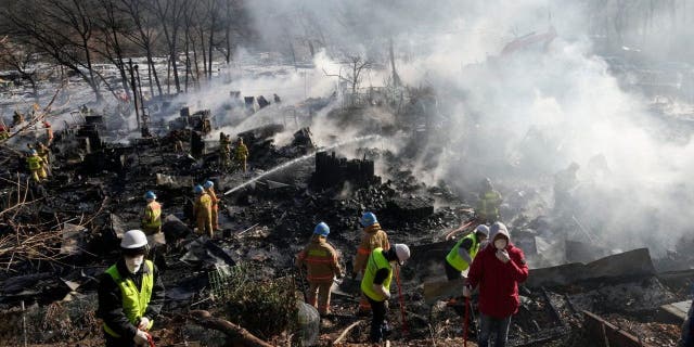 Firefighters and rescue workers clean up the site of a fire at Guryong village in Seoul, South Korea, Friday, Jan. 20, 2023. A fire spread through a neighborhood of densely packed, makeshift homes in South Korea's capital Friday morning.
