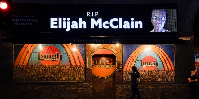 A man walks past a display showing an image of Elijah McClain outside Laugh Factory during a candlelight vigil for McClain in Los Angeles on Aug. 24, 2020. 