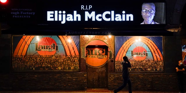 A man walks past a display showing an image of Elijah McClain outside Laugh Factory during a candlelight vigil for McClain in Los Angeles on Aug. 24, 2020. 