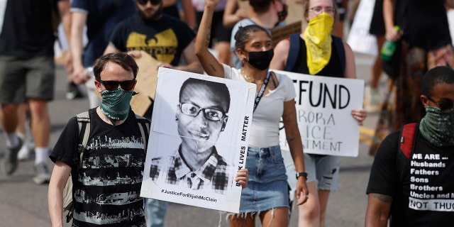 Demonstranten dragen borden terwijl ze over Sable Boulevard lopen tijdens een bijeenkomst en marcheren over de dood van Elijah McClain in Aurora, Colo., op 27 juni 2020.