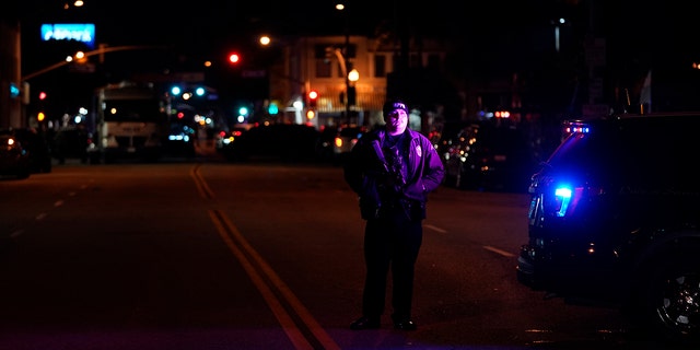 A police officer stands near a scene where a shooting took place in Monterey Park, Calif., Sunday, Jan. 22, 2023. 