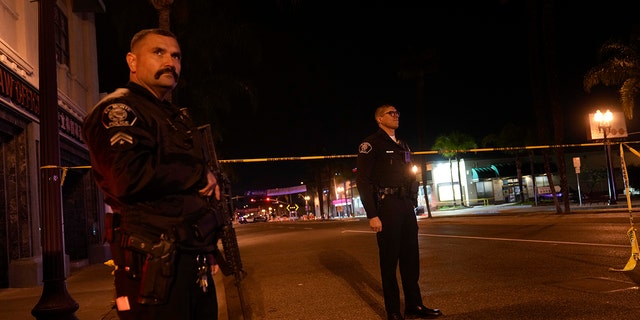 Two police officers stand guard outside the scene of a shooting in Monterey Park, California on Sunday, January 22, 2023. 