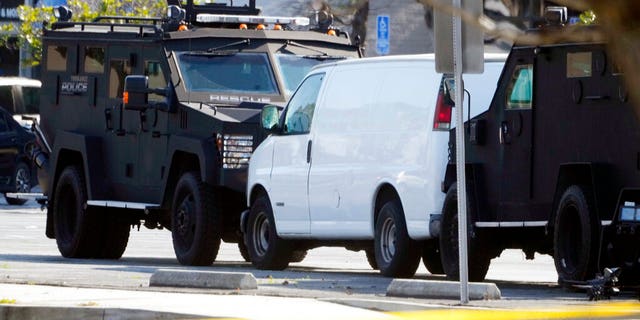 A van is surrounded by SWAT personnel in Torrance Calif., Sunday, Jan. 22, 2023. A mass shooting took place at a dance club following a Lunar New Year celebration, setting off a manhunt for the suspect.  (AP Photo/Damian Dovarganes)