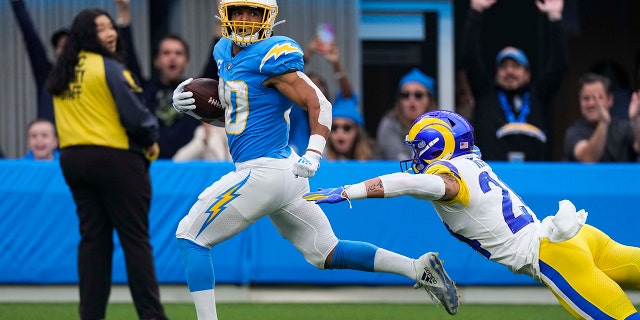 El corredor de los Chargers de Los Ángeles, Austin Ekeler (30), escapa de una entrada del profundo de los Rams de Los Ángeles, Taylor Rapp, mientras corre hacia la zona de anotación para anotar durante la primera mitad de un partido de fútbol americano de la NFL el domingo 1 de enero de 2023, en Inglewood, EE. California 