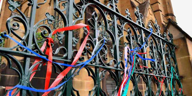 Ribbons are tied onto a fence at a protest at St Mary's Cathedral, in Sydney, on Jan. 31, 2023. Police plan to ask a judge to ban protesters from demonstrating outside St. Mary's Cathedral during Cardinal George Pell's funeral on Thursday.