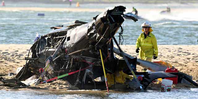 An emergency worker can be seen above standing next to a crashed helicopter following a collision near SeaWorld, on the Gold Coast, Australia, on Jan. 2, 2023. A 10-year-old Australian boy remained in a coma as of Jan. 6 following the crash.
