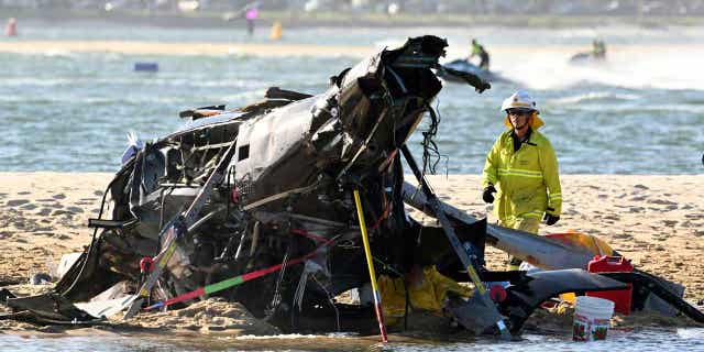 An emergency worker can be seen above standing next to a crashed helicopter following a collision near SeaWorld, on the Gold Coast, Australia, on Jan. 2, 2023. A 10-year-old Australian boy remained in a coma as of Jan. 6 following the crash.