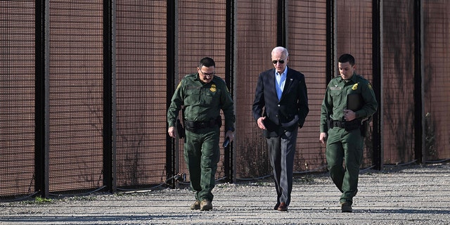 Le président américain Joe Biden s'entretient avec un membre de la US Border Patrol alors qu'ils marchent le long de la barrière frontalière américano-mexicaine à El Paso, Texas, le 8 janvier 2023. 