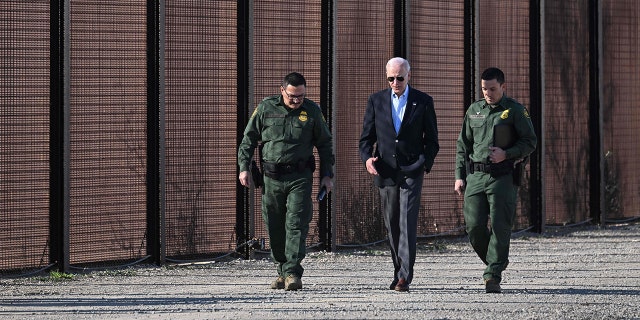 El presidente de los Estados Unidos, Joe Biden, habla con un miembro de la Patrulla Fronteriza de los Estados Unidos mientras caminan a lo largo de la valla fronteriza entre Estados Unidos y México en El Paso, Texas, el 8 de enero de 2023. 