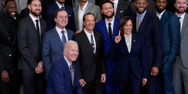 El presidente Joe Biden se arrodilla durante una foto grupal con la vicepresidenta Kamala Harris y miembros de los Golden State Warriors, campeones de la NBA de 2022, en un evento en el Salón Este de la Casa Blanca en Washington, el martes 17 de enero de 2023.