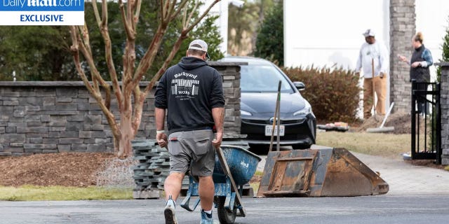 Man presumably working for a landscaping company moving material around the worksite at President Biden's vacation home in Delaware. President Biden is having a wall built around his beach house despite calls against a wall at the southern border.