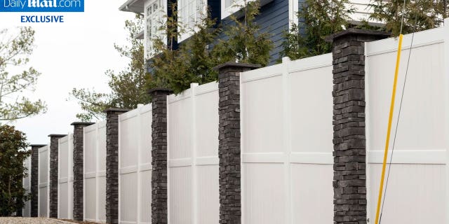 A white fence with stone columns around President Biden's vacation beach house in Delaware. President Biden has recently constructed a wall around his property.