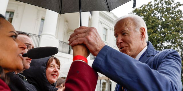 President Biden held NBC correspondent Kristen Welker's hand as he stepped underneath her umbrella to answer her question.