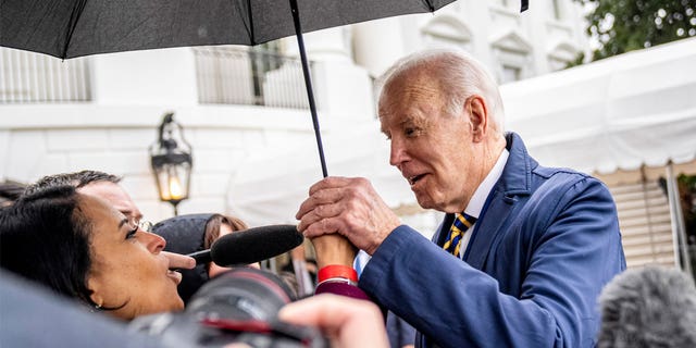 President Joe Biden steps under NBC White House correspondent Kristen Welker's umbrella to answer questions on the South Lawn of the White House before boarding Marine One in Washington, Tuesday, Jan. 31, 2023, for a short trip to Andrews Air Force Base, Md., and then on to New York.