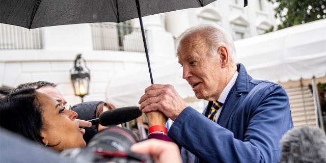 President Joe Biden steps under NBC White House correspondent Kristen Welker's umbrella to answer questions on the South Lawn of the White House before boarding Marine One in Washington, Tuesday, Jan. 31, 2023, for a short trip to Andrews Air Force Base, Md., and then on to New York.